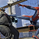 Spider-man kicks a masked villain on top of a skyscraper.